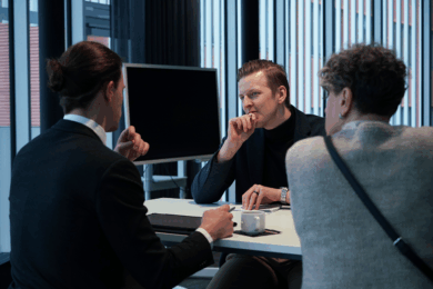 Asiantuntija keskustelee kahden asiakkaan kanssa, jotka ovat selkäpäin kameraan.