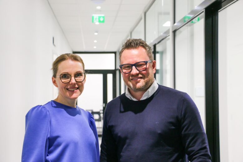 Two people seated at a table presenting a range of eye care products arranged in a row.