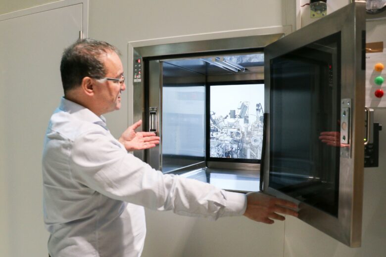In a laboratory setting, a person opens a protective enclosure and presents the research equipment inside.
