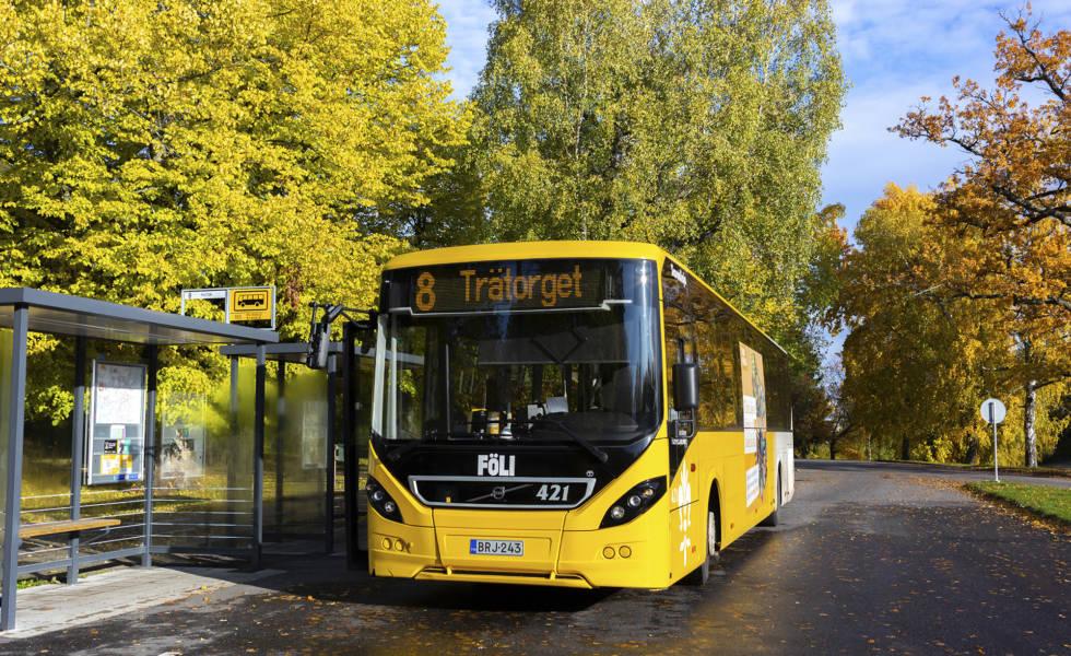 Keltainen kaupunkiliikenteen bussi seisoo pysäkillä syysauringossa.